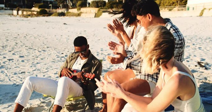 People Listening to a Man Playing the Guitar on the Beach