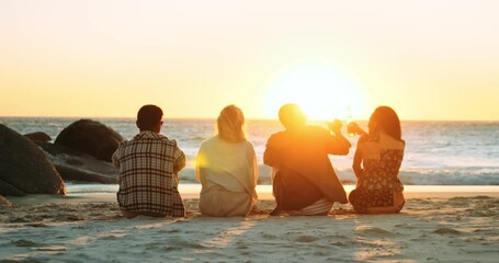 Four Friends on the Beach Watching the Sunset and Raising Glasses