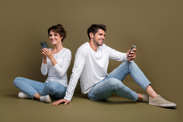 Full length photo of cheerful cute married couple wear white shirts texting twitter telegram...