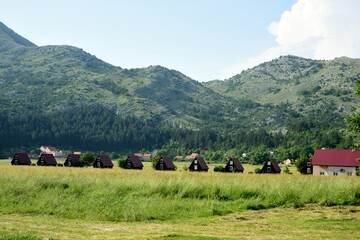 Montenegro LANDSCAPE WITH WOODEN TOURIST HOUSES ON THE BACKGROUND OF MOUNTAINS, CAMPING, HOTEL