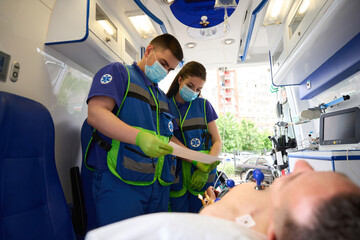 Team of paramedics makes a cardiogram to man in ambulance © Svitlana