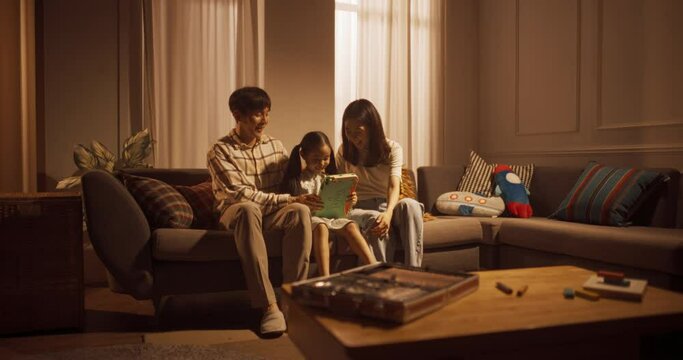 거실에서 함께 웃으며 태블릿으로 게임을 즐기는 부모와 딸의 와이드 샷