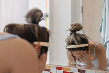 Asian Thai woman face down washing cleaning and massage, using cleansing foam, in the mirror, water spread in the bathroom.