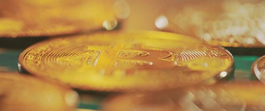 Golden cryptocurrency coins on dark surface; close-up shallow focus reveal