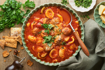 Soup. Fresh tomato soup with meatballs, pasta, vegetables and parsley in green rustic bowl on...