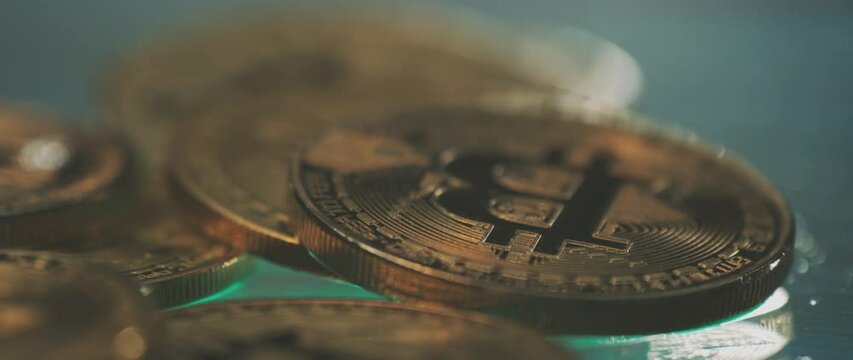 Golden cryptocurrency coins on dark surface; close-up shallow focus reveal