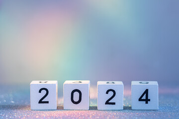 2024 New Year Coming. White Wooden Blocks With 2024 Number On Glitter Texture In Neon Light
