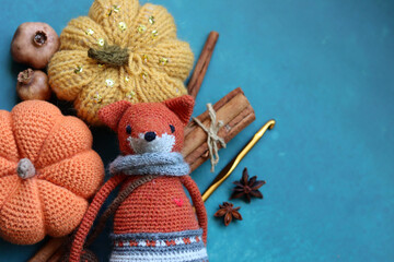 Fototapeta premium Knitted toy fox, yarn balls and autumn decorations on a gray background with space for text. Cute amigurumi toy. 