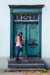 young woman is standing at the old green door