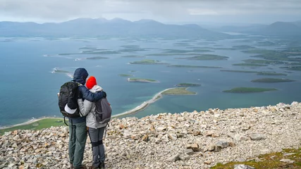 Couple resting and enjoying view on a path to the top of Croagh Patrick mountain. County Mayo, Ireland. Popular landmark for pilgrimage and hiking. © Marcin