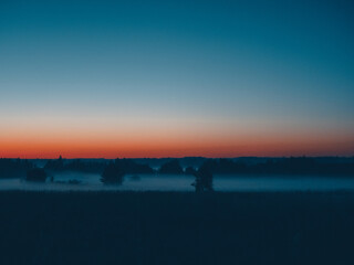 Sunset with mist and bright colors. Fog in the meadow