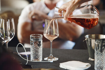 Sommelier school. Professional wine waiter pouring wine into decanter to the glasses during alcoholic beverages training for staff. Blind wine degustation.