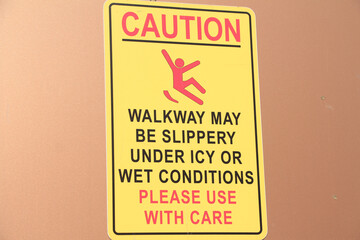 caution walkway may be slippery under icy or wet conditions please use with care vertical rectangle sign with illustration picture of person slipping, yellow black red