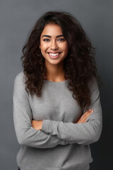 Obraz premium Portrait of a young latin woman with pleasant smile and crossed arms isolated on grey wall.
