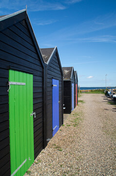 Fishing sheds lined up on a dirt road with brightly colored doors, Denmark
