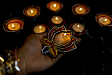 Happy Diwali - Woman hands with henna holding lit candle isolated on dark background.