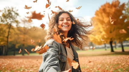 Foto auf Acrylglas Woman drop leaves in autumn park. Beautiful joyful woman enjoy, having fun at the autumn season at park. Fall season fashion.   © BlazingDesigns