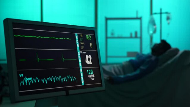 Close-up video capturing intencive care unit showing heart and pressure rate. Blurred silhouette of a patient dying on the background. Lines go straight on the monitor.