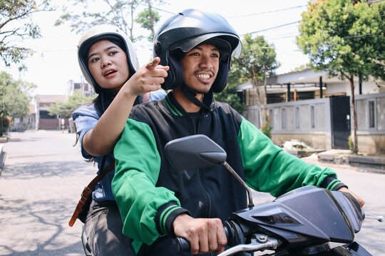 Female passenger directing destination to motorcycle taxi driver 