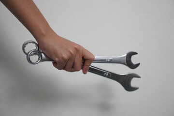 Human hand holding a wrench isolated on white background. Closeup. High resolution product. The mechanic's hand holds a wrench behind himself. Mechanic holding wrench for car repair