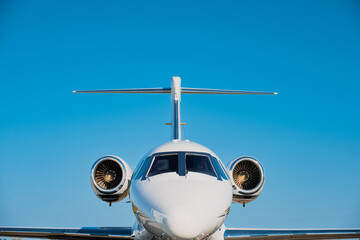 Small corporate jet seen head on.  Clear blue sky in the background.