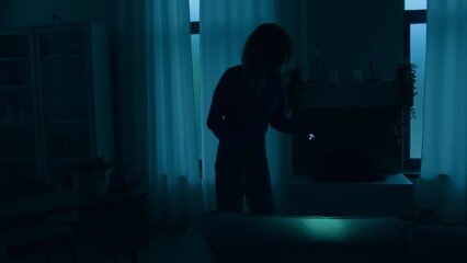 Woman girl lady female walking indoors in dark living room at night power war blackout electricity energy crisis outage searching lost things with flashlight at home without lights apartment darkness