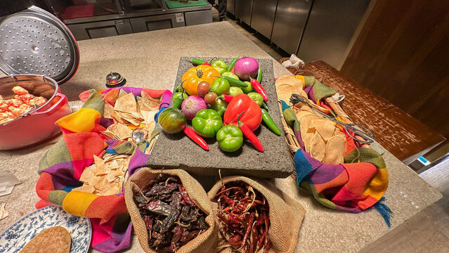 Red and green tomatoes, both fresh and dried chiles on top of a metate