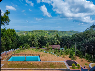 Beautiful outside view from the resort , swimming pool near the land with meadow  and green trees and valleys under the blue sky 