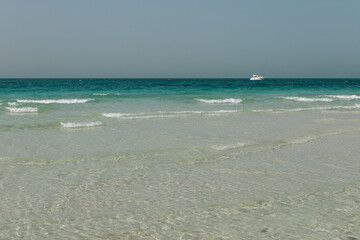 Fototapeta na wymiar Blue clear sea, yacht, water, waves, clear sky. beach in Saadiyat island, United Arab Emirates. Beautiful seascape.