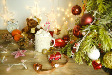 beautiful holiday composition with decorated New Year's tree, garlands, lights, candles, mug of hot cocoa with marshmallows, New Year Atmosphere, Holiday Magic