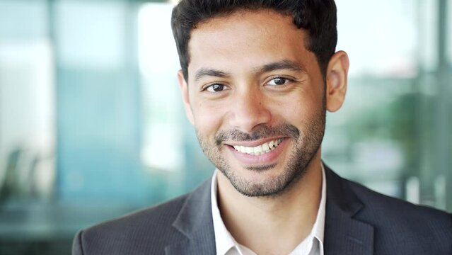 Close up. Portrait of a young successful businessman in a formal suit at a workplace in a business office. Confident smiling entrepreneur with a friendly look looking at camera. Head shot of a manager