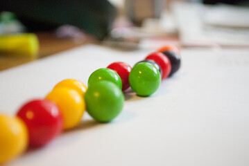 A row of colorful gumballs on a white piece of paper with a faded background. Gumballs are green,...