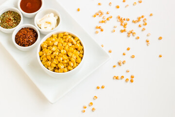 Natural, freshly boiled corn grains with various spices designed on a white plate