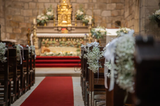 Floral ornamentation inside a worship space, church. Festive decoration for wedding event. Flower arrangements predominantly white and green.