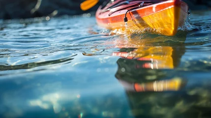 Fotobehang : A close-up of a birthday kayak's paddle dipping into the glassy waters. © Nazia