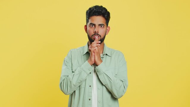 Stressed depressed Indian man terrified about danger problems, suffering phobia, anxiety disorder, expresses fear, waving no, insecure, stress, panic. Scared fearful guy on yellow studio background
