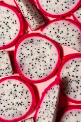 Slices of fresh white pitaya or dragon fruit on pink background, flat lay