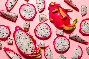 Slices of fresh white pitaya or dragon fruit on pink background, flat lay