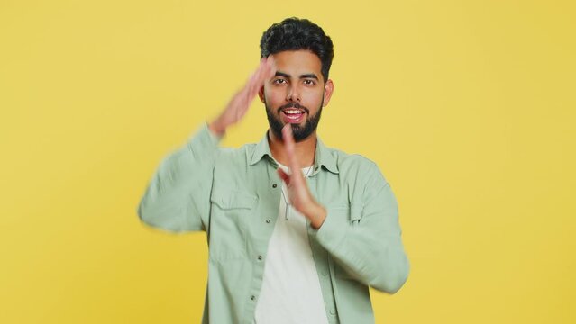Tired serious upset Indian young man showing time out gesture, limit or stop sign, no pressure, I need more time, take a break, relax, rest, help. Arabian guy isolated on yellow studio background