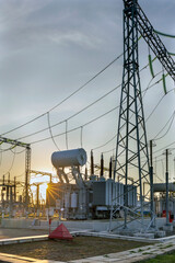 High voltage electrical transformer at sunset.