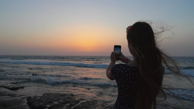 young woman on the beach taking photo 