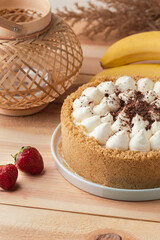 Banoffee cake with banana and caramel sauce filling sprinkled with grated dark chocolate on the wooden rustic background. English traditional pie