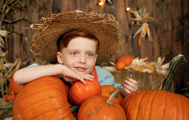 boy in orange overalls and straw hat harvesting pumpkins