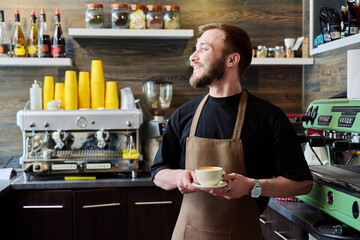 Portrait of barista male in an apron with freshly prepared cappuccino coffee