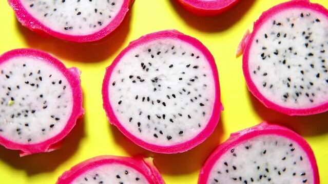 Slices of fresh white pitaya or dragon fruit on yellow background, flat lay. Concept of exotic tropical and vegan food. 360 degrees rotation