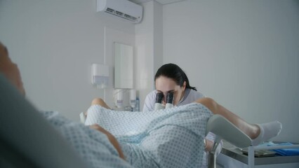 Gynecology room in hospital. Female gynecologist uses colposcope, takes tests from patient. Woman lies on gynecological chair during colposcopy procedure. Preparation for pregnancy. Modern clinic.