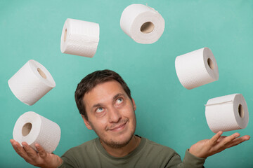 A thrifty and greedy man juggles rolls of toilet paper.