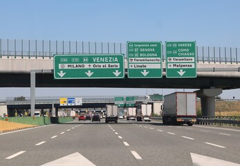 motorway junction with directions to the Italian cities and road junctions with trucks and cars - obrazy, fototapety, plakaty