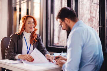 Business people man and woman sitting at the table in the office and signing the contract.