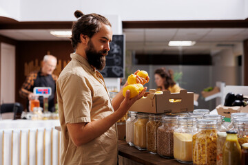 Green living man purchasing lemons grown by sustainable zero waste supermarket owner in his garden....